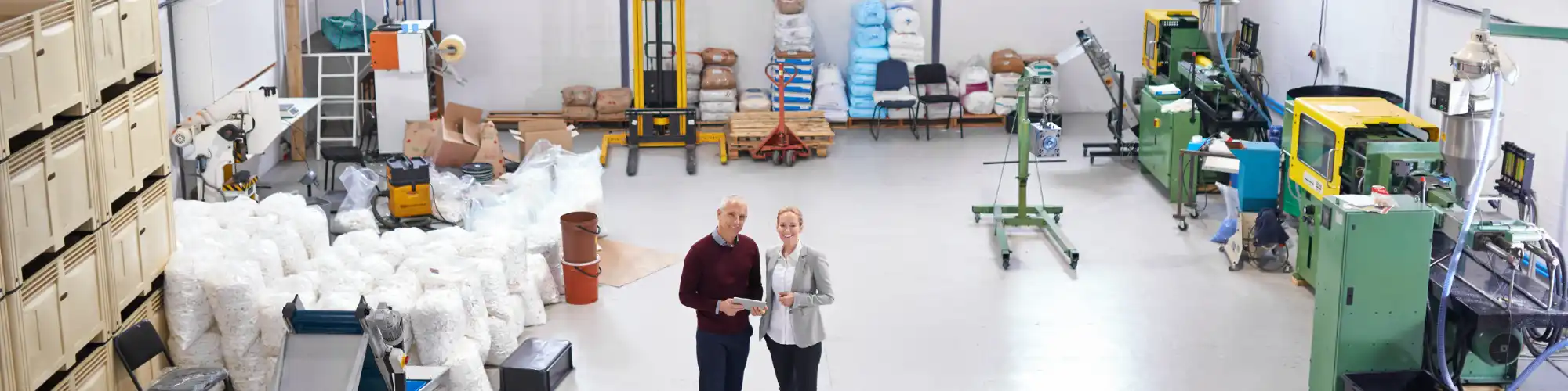 Eine Frau und ein Mann stehen in einer kleinen Halle und blicken in die Kamera